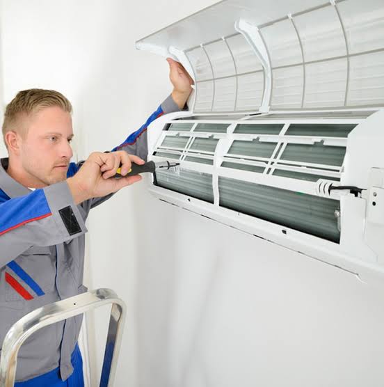 HVAC technician cleaning a wall-mounted indoor air conditioning unit