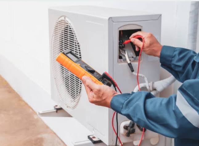 Technician testing an outdoor air conditioning unit with electrical diagnostic tools