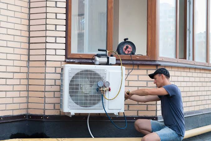 Technician adjusting an outdoor heat pump beside a home