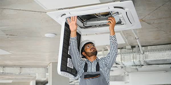 Technician servicing a ceiling-mounted HVAC system during installation