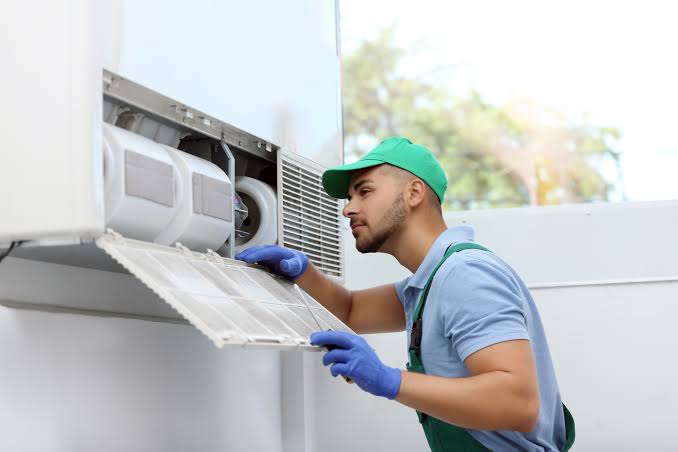 Technician cleaning the filter of an indoor air conditioning unit
